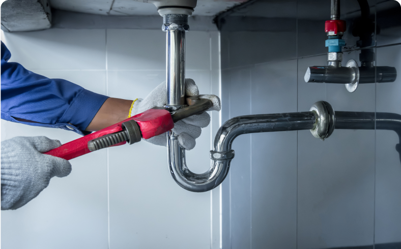 Plumber fixing pipe with a red wrench.