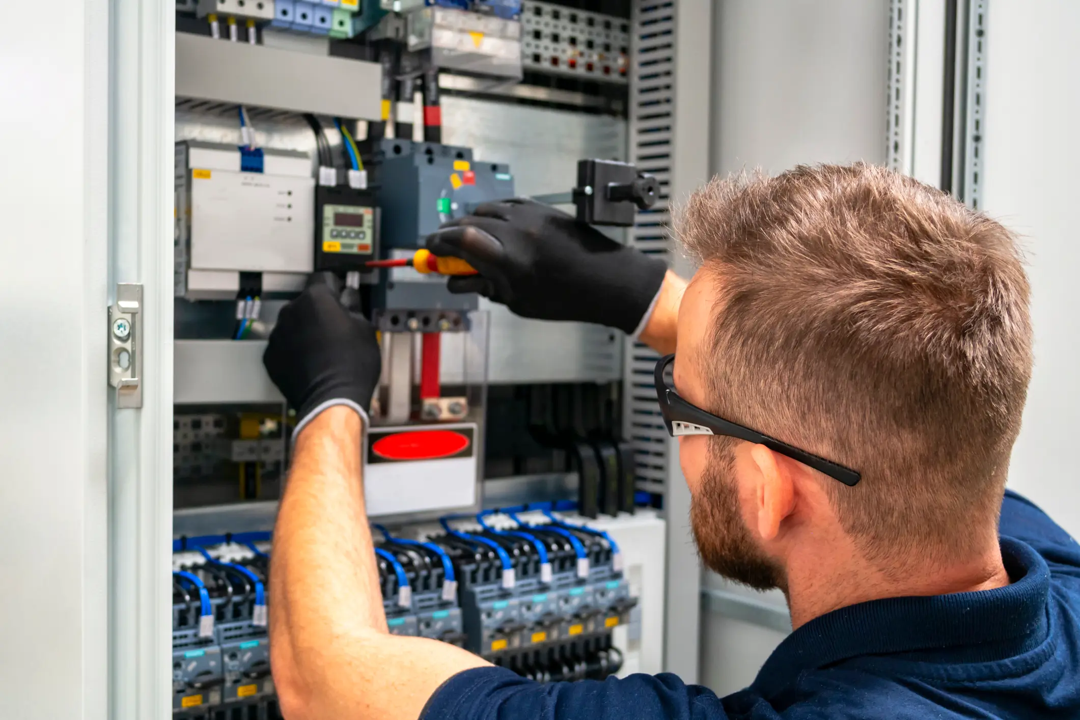 Technician working on electrical panel wiring.