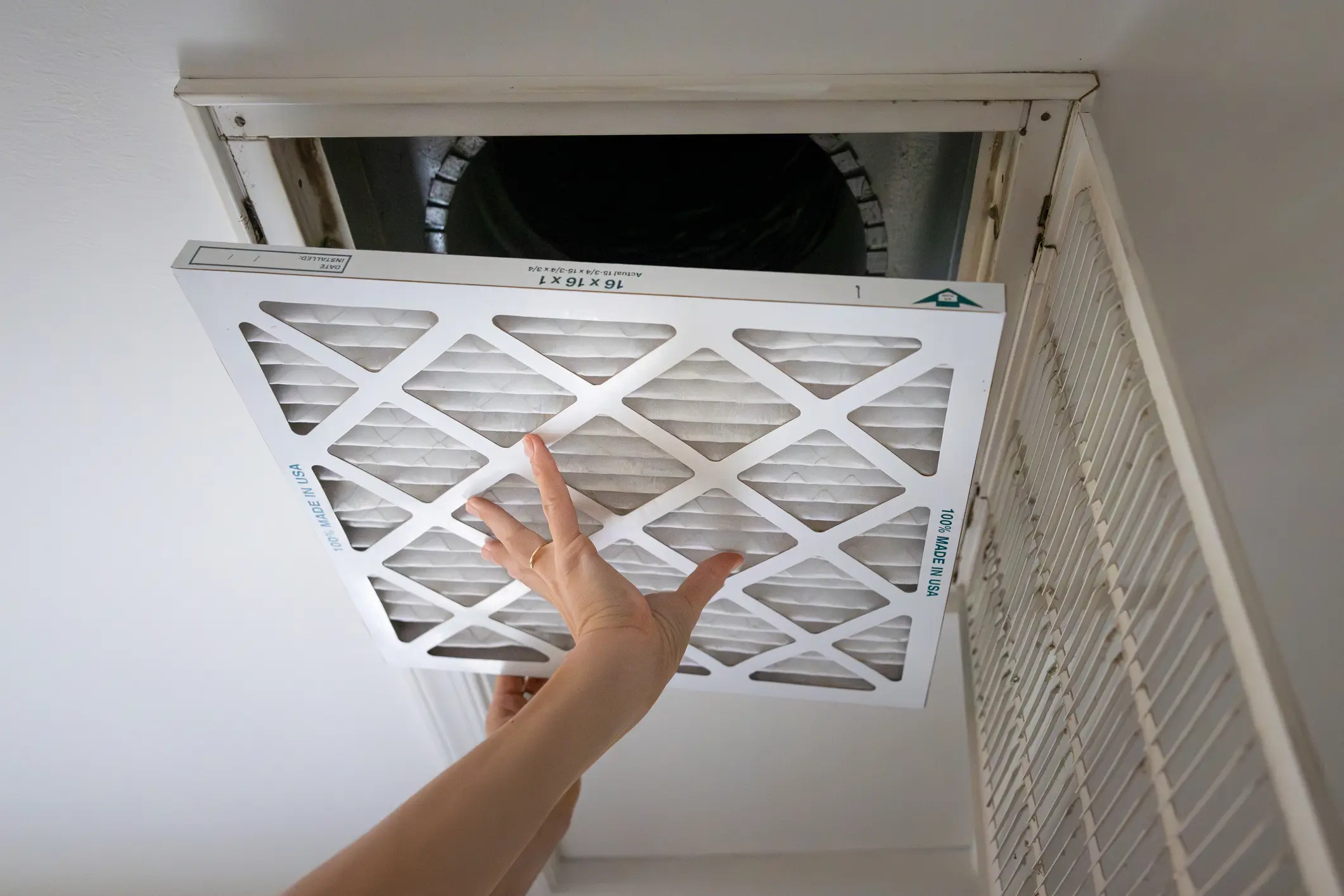 Inserting air filter into ceiling vent.