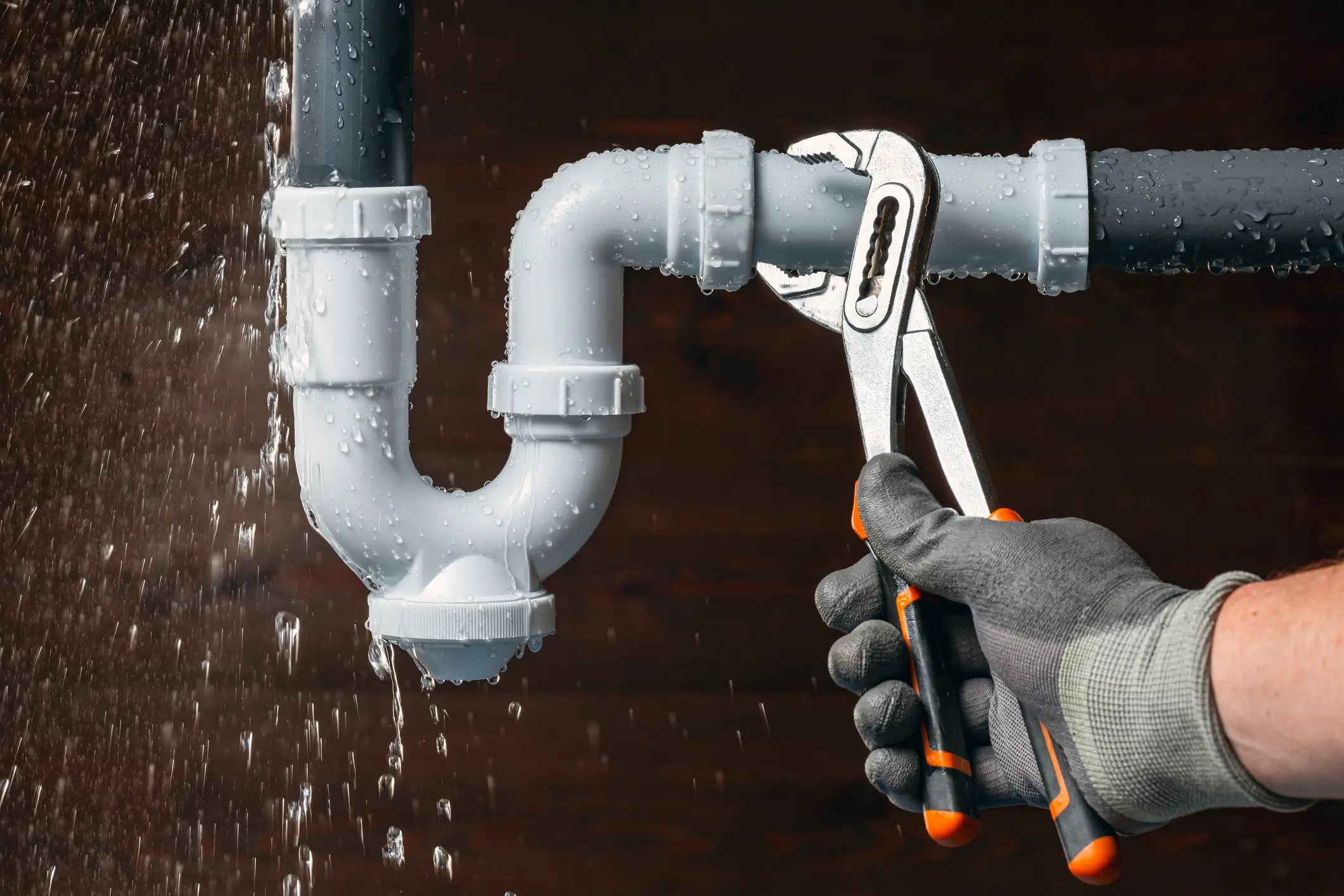 Plumber fixing leaking pipe with wrench.